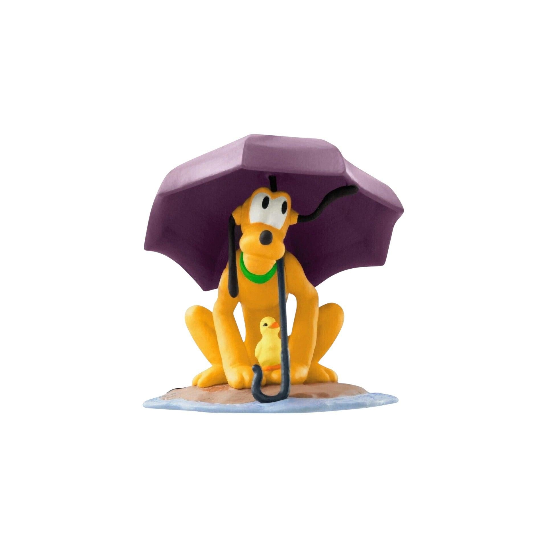 Figurine of a dog with a purple umbrella and a duckling underneath on a white background