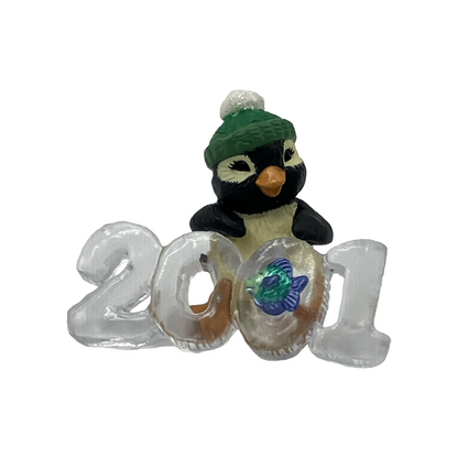 Penguin figurine wearing a green hat with '2021' on a white background