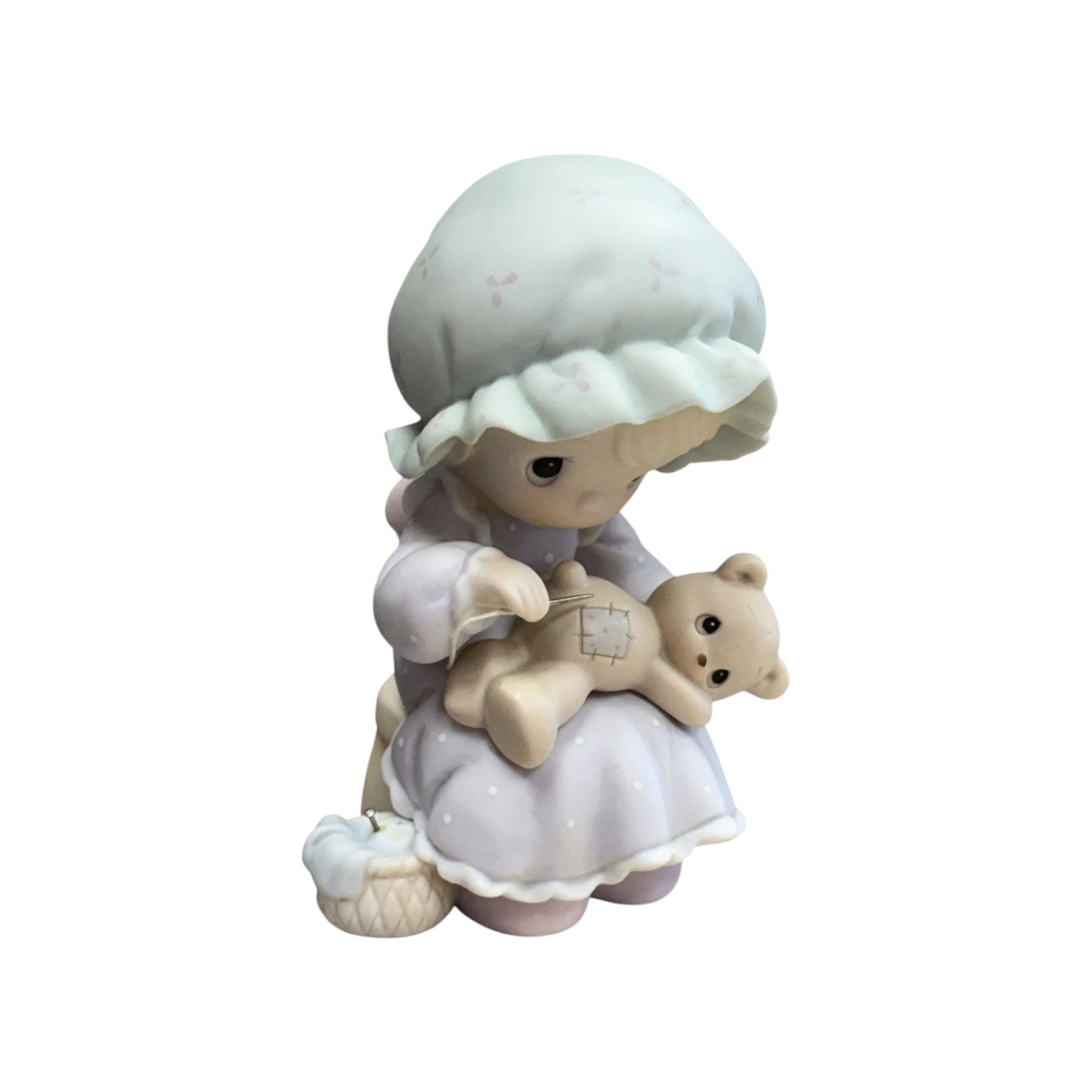 Adorable girl sews patch onto beloved teddy bear