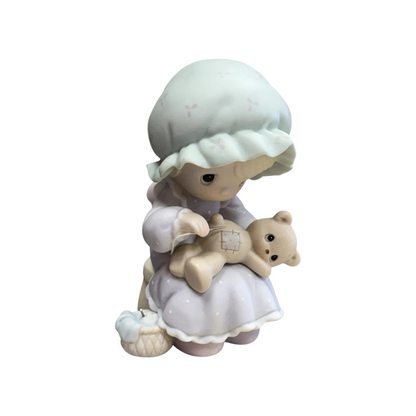 Adorable girl sews patch onto beloved teddy bear