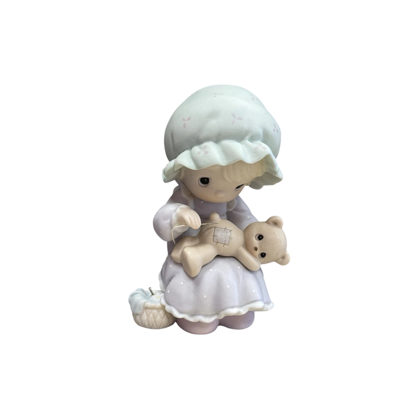 Adorable girl sews patch onto beloved teddy bear