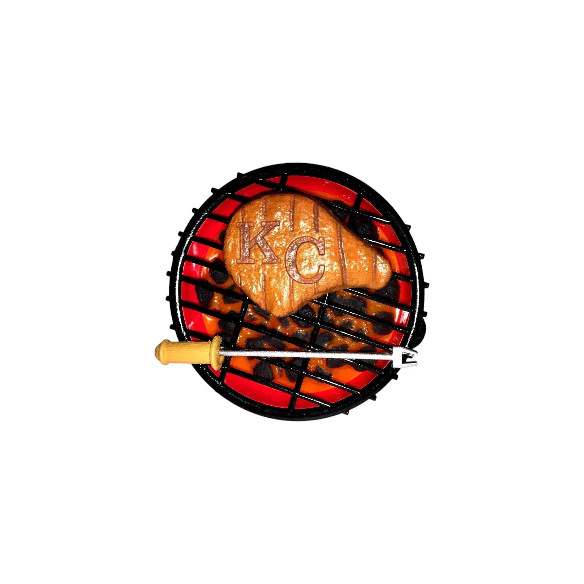 Grilled chicken breast on a miniature grill with 'K.C.' branding on a white background