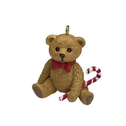 Teddy bear ornament with a candy cane on a white background
