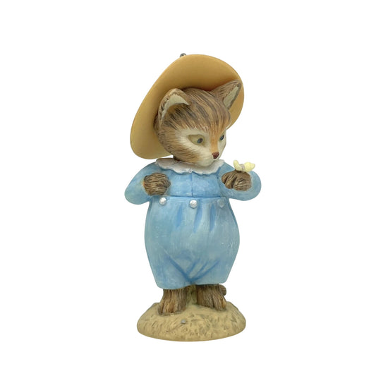 Figurine of a fox in a blue outfit and brown hat holding a butterfly on a white background