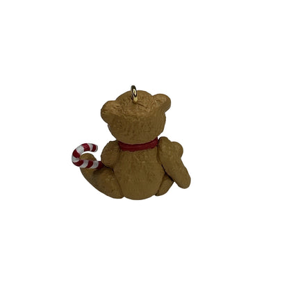 Brown teddy bear with a red ribbon and candy cane on a white background