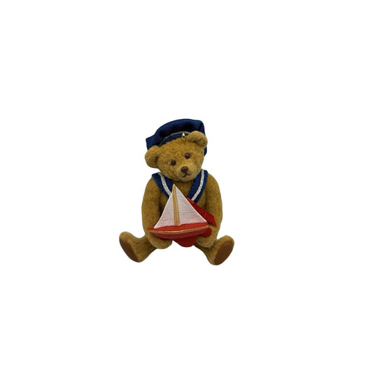 Teddy bear in a nautical outfit with a sailboat toy on a white background